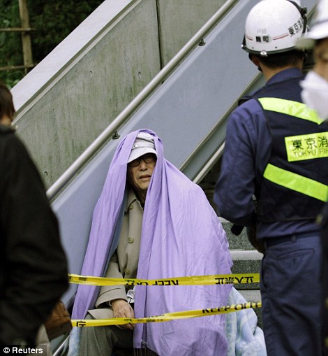 A man sits wrapped in a blanket after he was evacuated from a building in Tokyo's financial district, after an earthquake off the coast of northern Japan, March 11, 2011. 