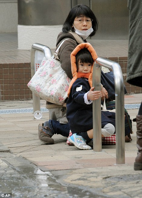 A mother and child crouch on a street in Tokyo while an earthquake hits Friday, March 11, 2011. 